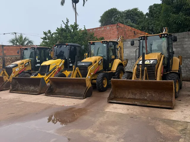 Retroescavadeiras Caterpillar e New Holland da SL alinhadas no pátio da base